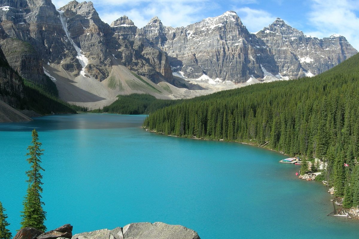 Turkisblå Moraine Lake omgitt av granskog og tinder i Banff nasjonalpark i Canada